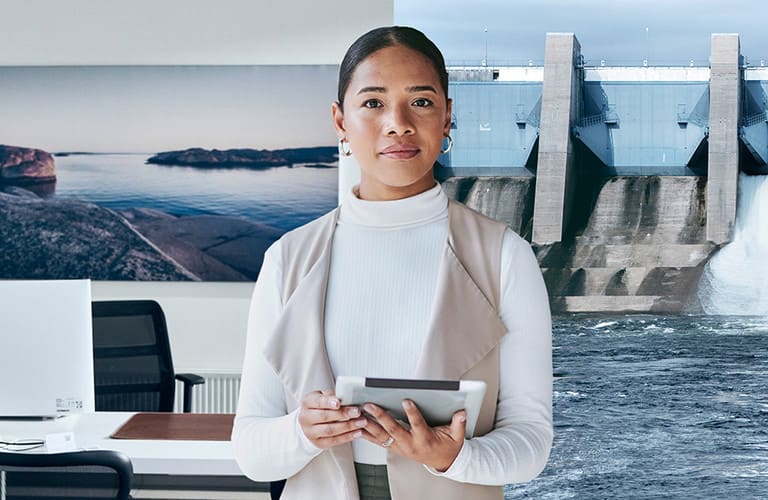 Frau hält Tablet in der Hand. Der Hintergrund zeigt ein Büroraum und eine Wasserkraftanlage.